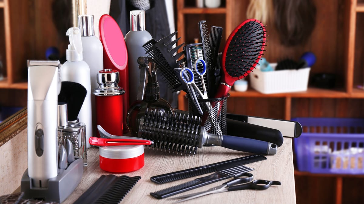 Matériel de coiffure et beauté sur une table : tondeuse, brosses, peignes, ciseaux et produits pour salon